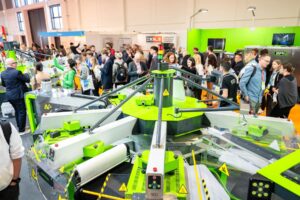Visitors gather around a carousel screen printing press on the textile show floor at FESPA Global Print Expo