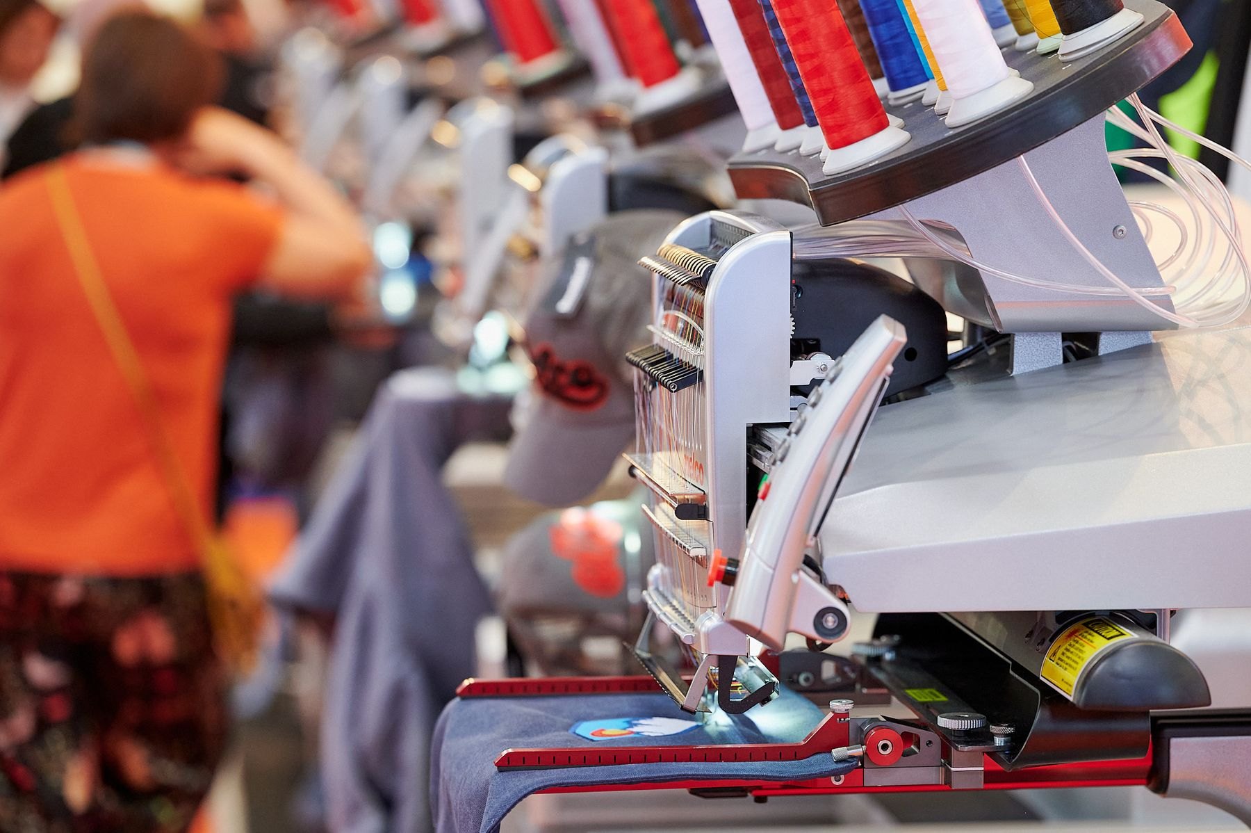 Multi-head embroidery machine stitching garments at a FESPA textile exhibition